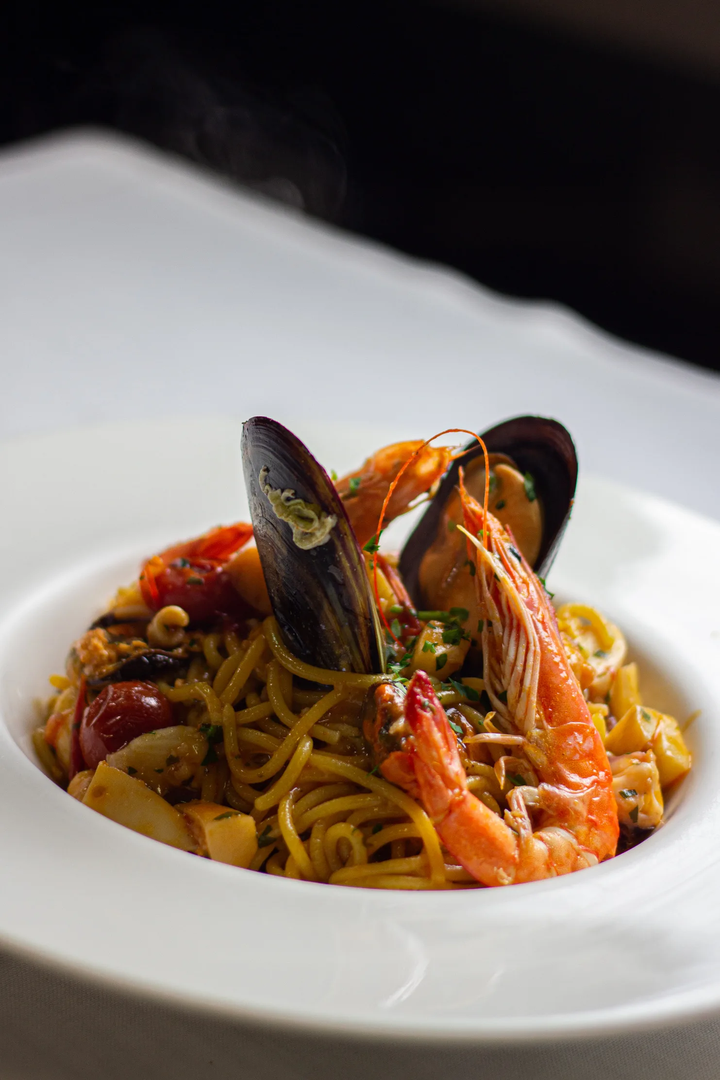 Pasta con mejillones y langostinos en plato blanco